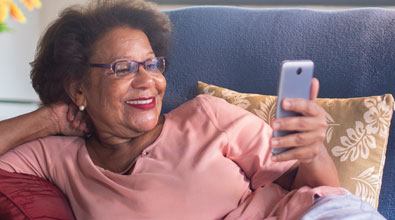Smiling senior black woman looking at her mobile phone. 